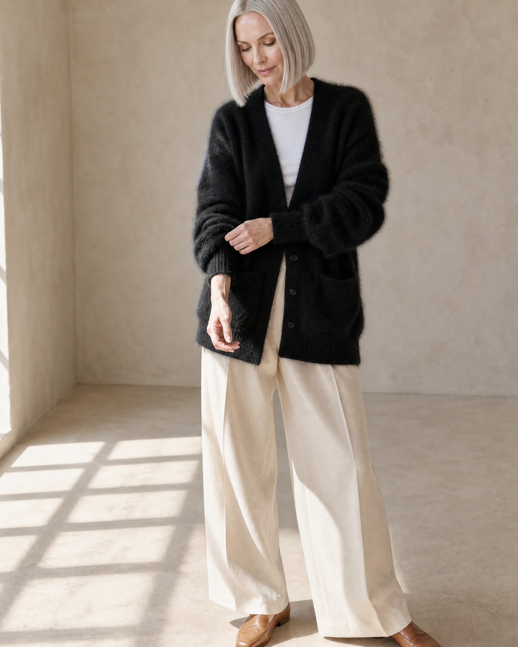 Women's V-Neck Button Cardigan with Pockets in Black, adjusting the sleeve, worn by model