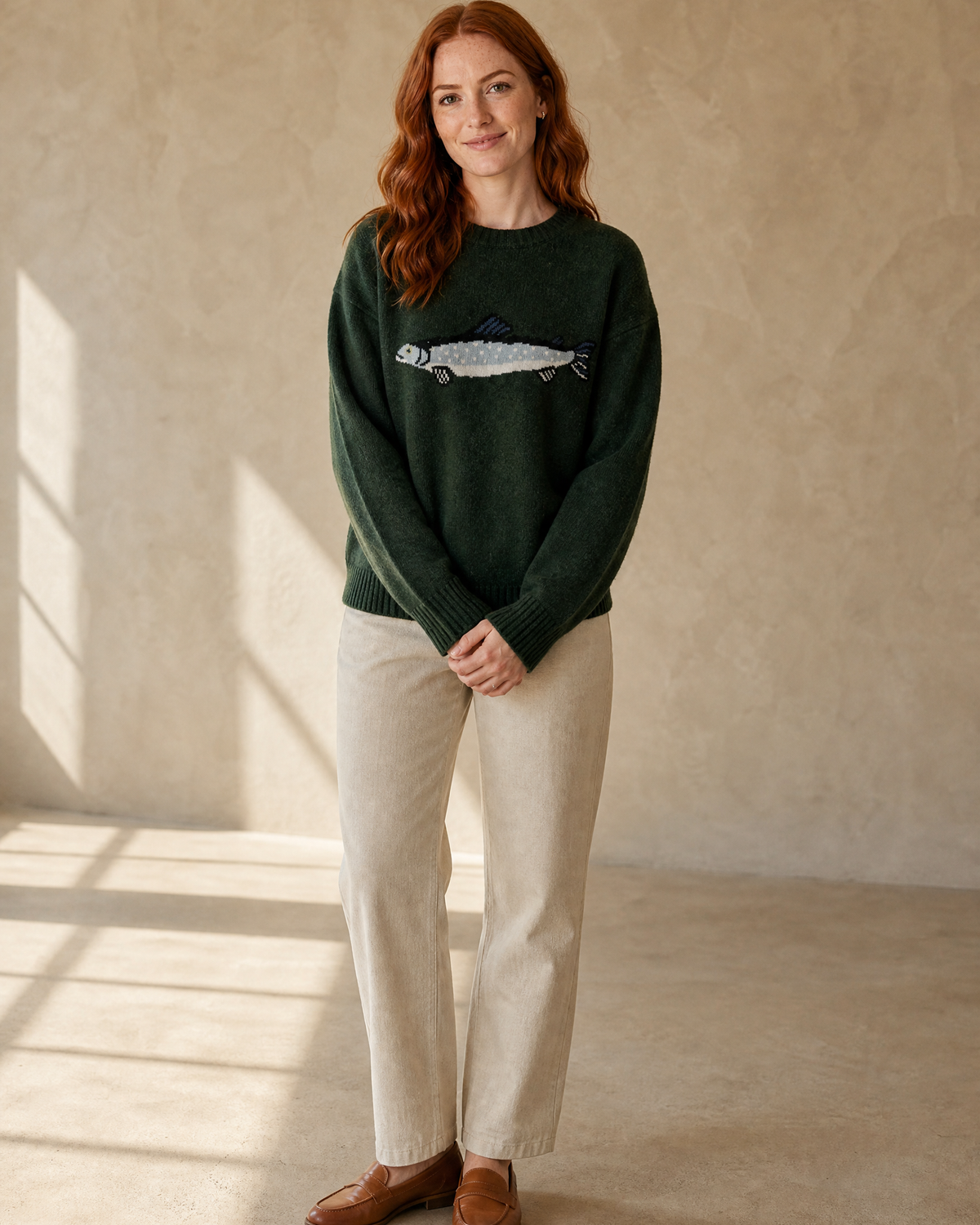 Women's Relaxed Fish Motif Knit Sweater in Dark Green, hands clasped front, worn by model