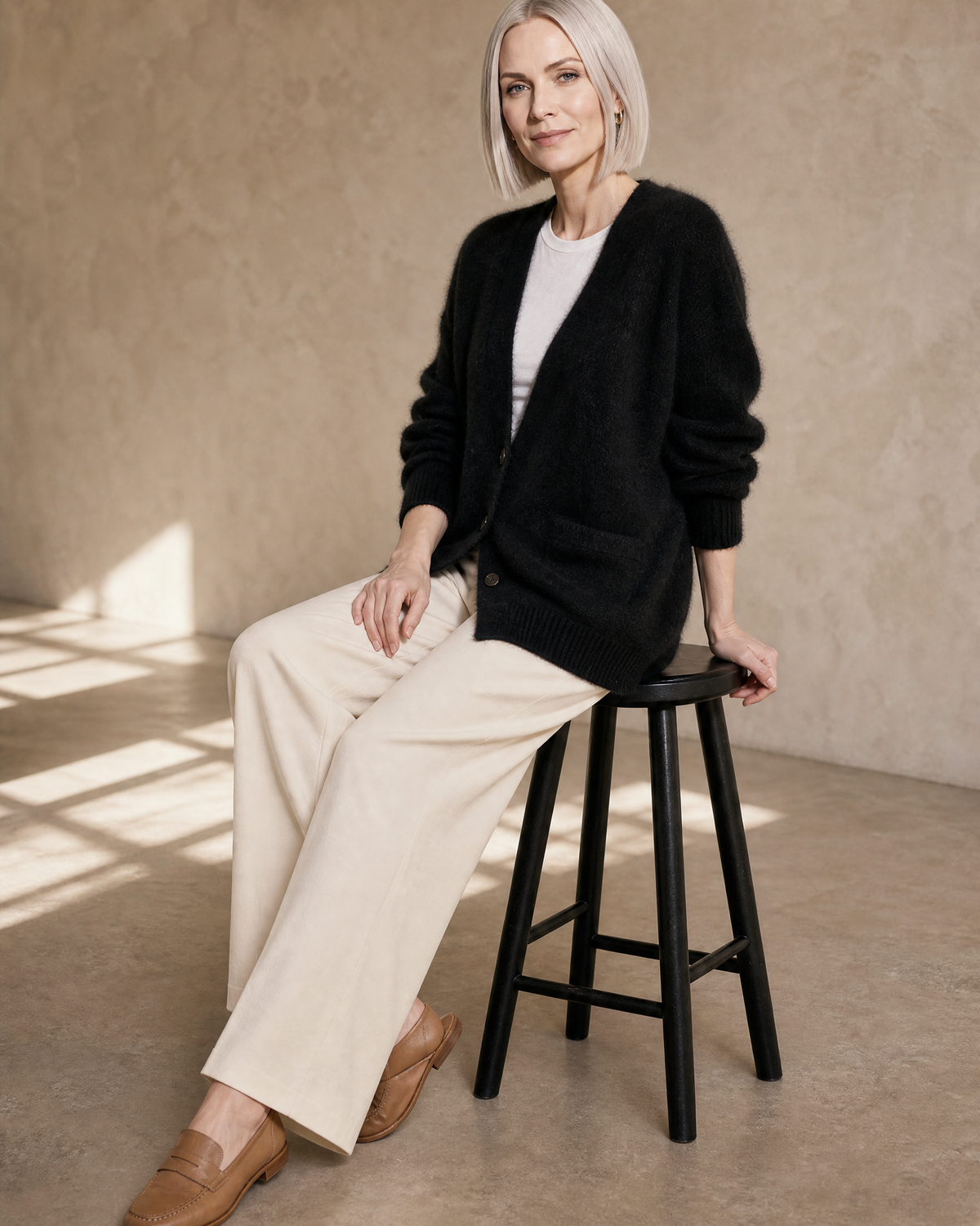 Women's V-Neck Button Cardigan with Pockets in Black, stool, side saddle profile, worn by model