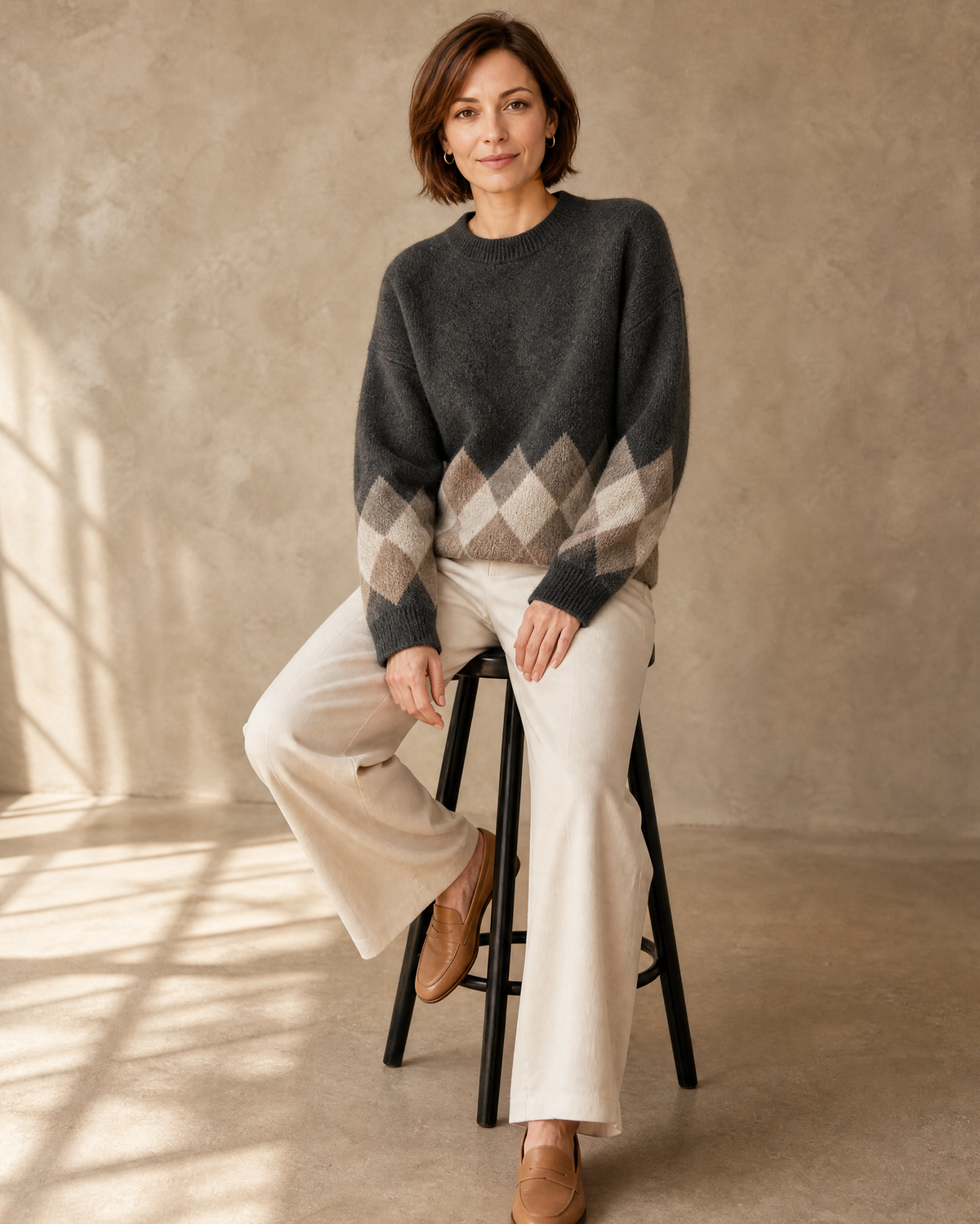Women's Colour Block Argyle Knit Sweater in Dark Gray, stool, leaning back, worn by model