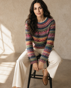 Women's Multicolour Patterned Crew Neck Sweater in Rose Red, perched on stool edge, worn by model