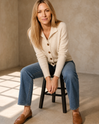 Women's Stand Collar Button Front Cardigan in Beige, perched on stool edge, worn by model
