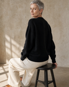Women's Relaxed Fish Motif Knit Sweater in Black, stool, back turned, worn by model