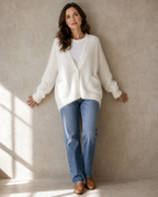 Women's V-Neck Button Cardigan with Pockets in White, back against wall, head turned, worn by model
