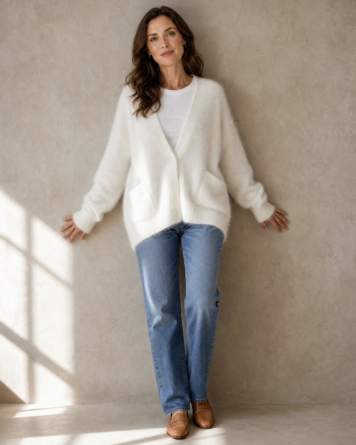 Women's V-Neck Button Cardigan with Pockets in White, back against wall, head turned, worn by model