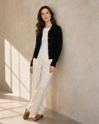 Women's Stand Collar Button Front Cardigan in Black, shoulder blade to wall, ankles crossed, worn by model
