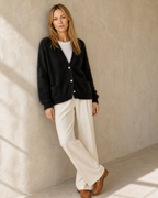 Women's Fuzzy Button Cardigan with Patch Pockets in Black, shoulder blade to wall, ankles crossed, worn by model