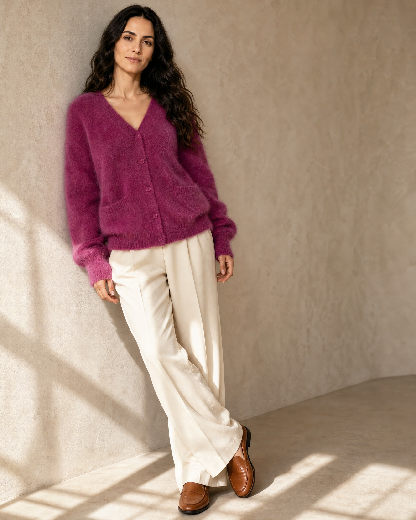 Women's V-Neck Button Cardigan with Pockets in Dark Violet, shoulder blade to wall, ankles crossed, worn by model