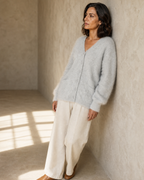 Women's V-Neck Button Cardigan with Pockets in Light Gray, wall lean, looking to the light, worn by model