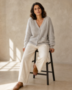 Women's V-Neck Button Cardigan with Pockets in Light Gray, stool, leaning back on hands, worn by model