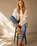 Women's V-Neck Button Cardigan with Pockets in Apricot, stool, one knee drawn up, worn by model
