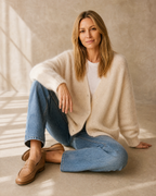 Women's V-Neck Button Cardigan with Pockets in Apricot, floor, one knee up, arm draped, worn by model
