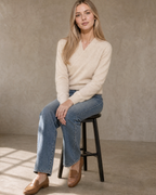 Women's Wrap V-Neck Knit Sweater for Everyday Layering in Vanilla beige, stool, side sit with hands on knee, worn by model