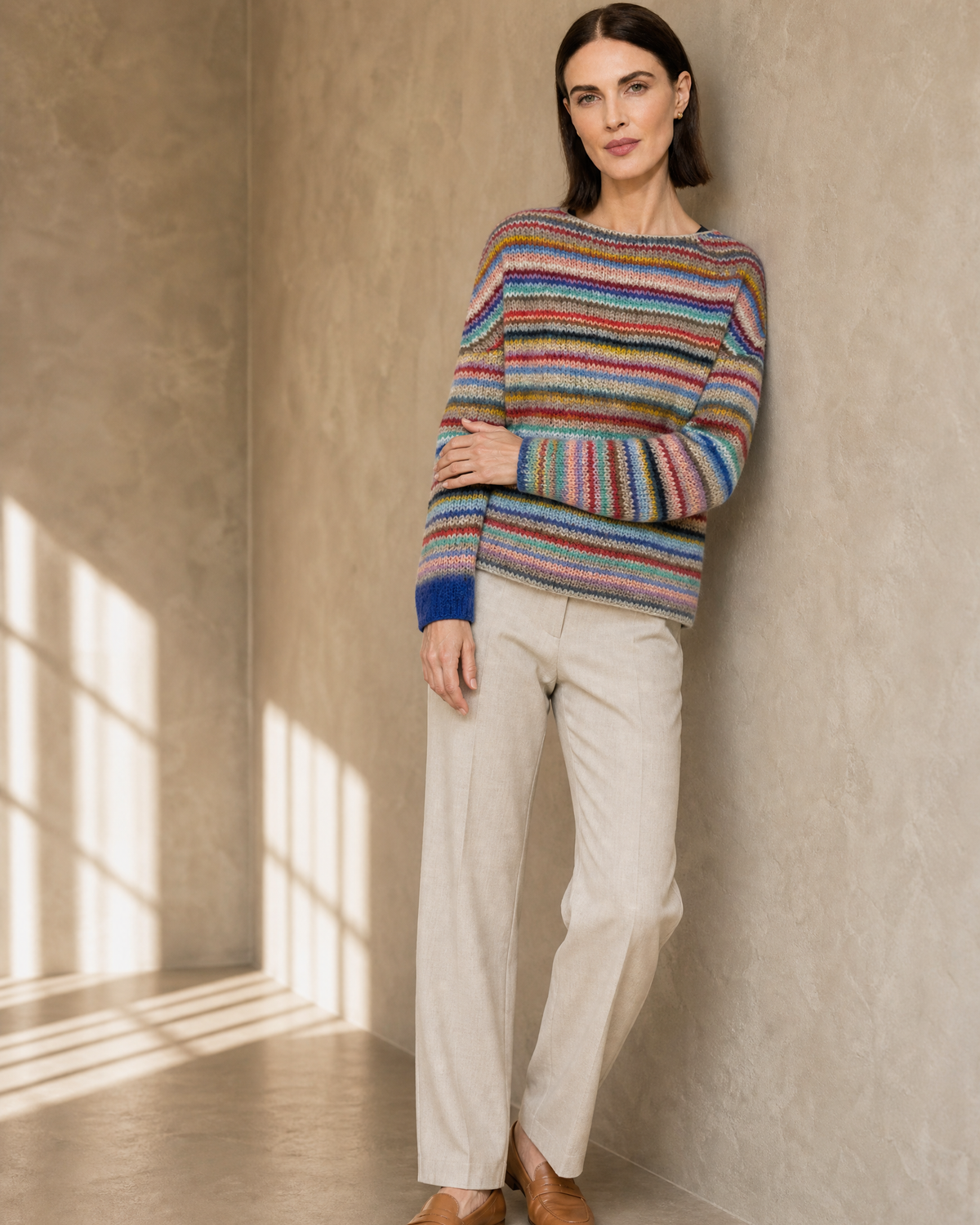 Women's Multicolour Patterned Crew Neck Sweater in Rainbow Bar, wall lean, one hand at sleeve, worn by model