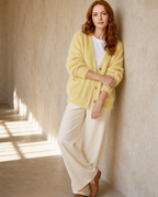 Women's V-Neck Button Cardigan with Pockets in Yellow, wall lean, one hand at sleeve, worn by model