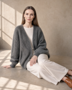 Women's V-Neck Button Cardigan with Pockets in Dark Gray, floor, legs extended to one side, worn by model